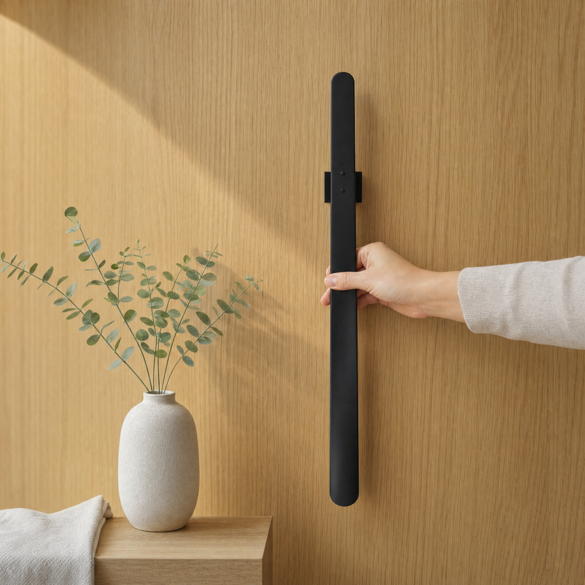 Magnetische schoenlepel in mat zwart tegen licht eiken houten wandpaneel