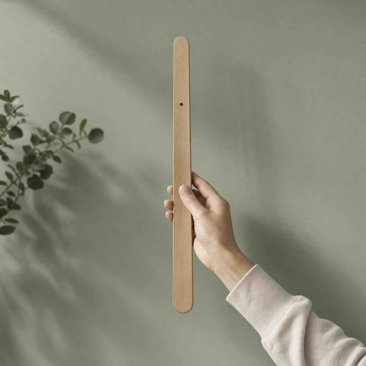 Magnetische schoenlepel in licht eiken tegen saliegroene muur
